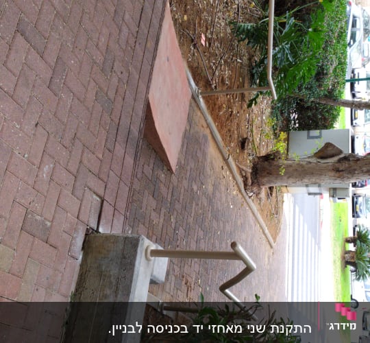 מעקה מתכת לאורך שביל מרוצף בלבנים אדומות